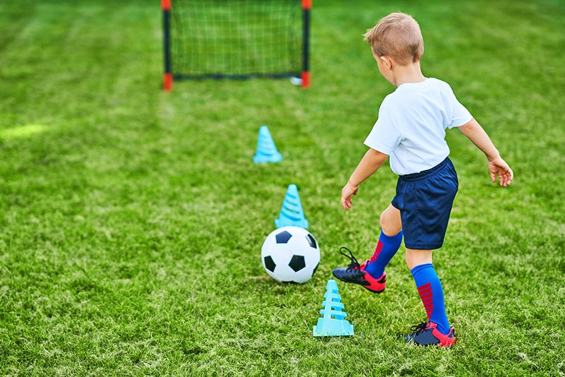 Little Boy practising soccer outdoors