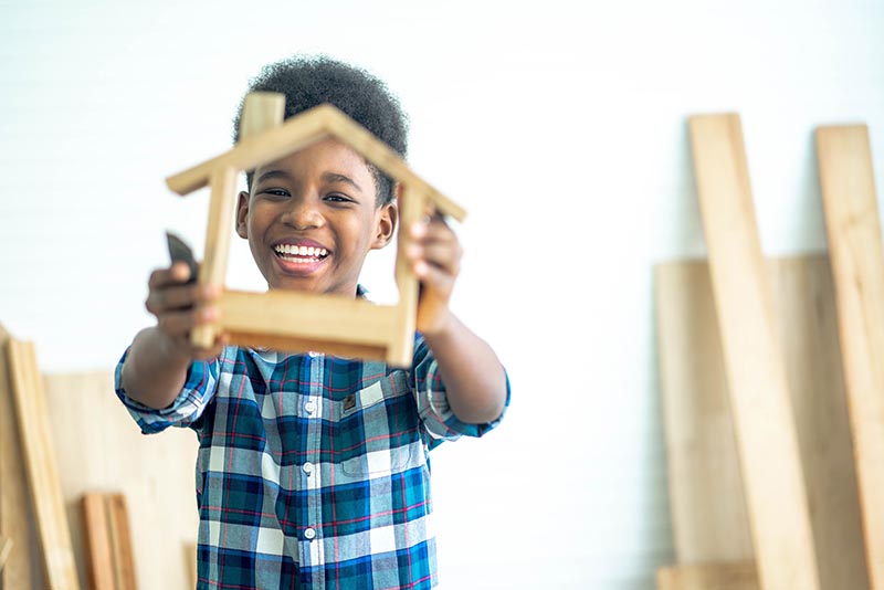 Smiling kid happy working with wood handyman creating frame comf